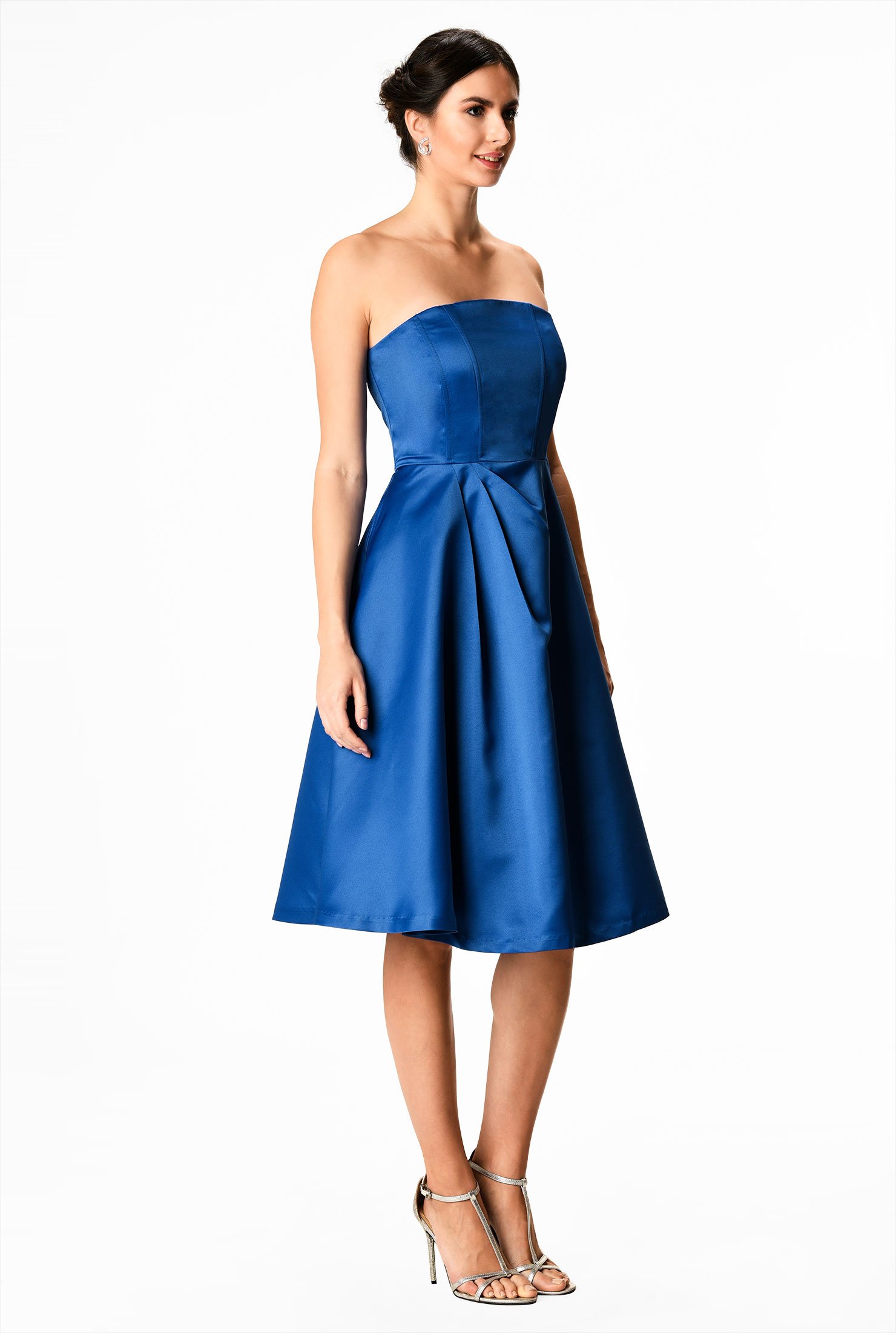 Our polydupioni dress is styled with a strapless bodice and flared out to a full skirt with asymmetric angled pleats.