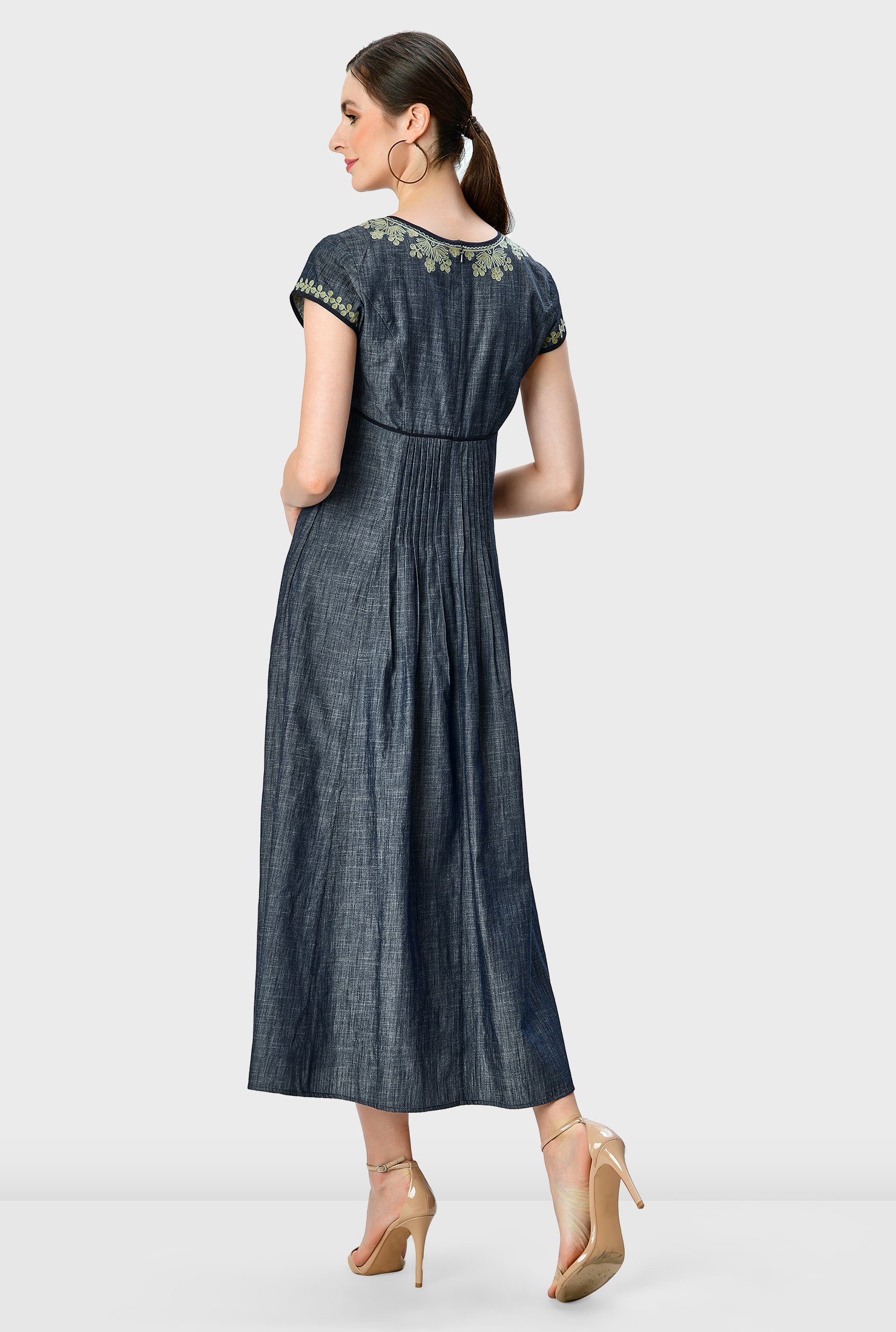 Artful embroidery blooms on our light cotton chambray dress fashioned with front and back pintuck pleats that release from the contrast empire waist to the full flare skirt. 