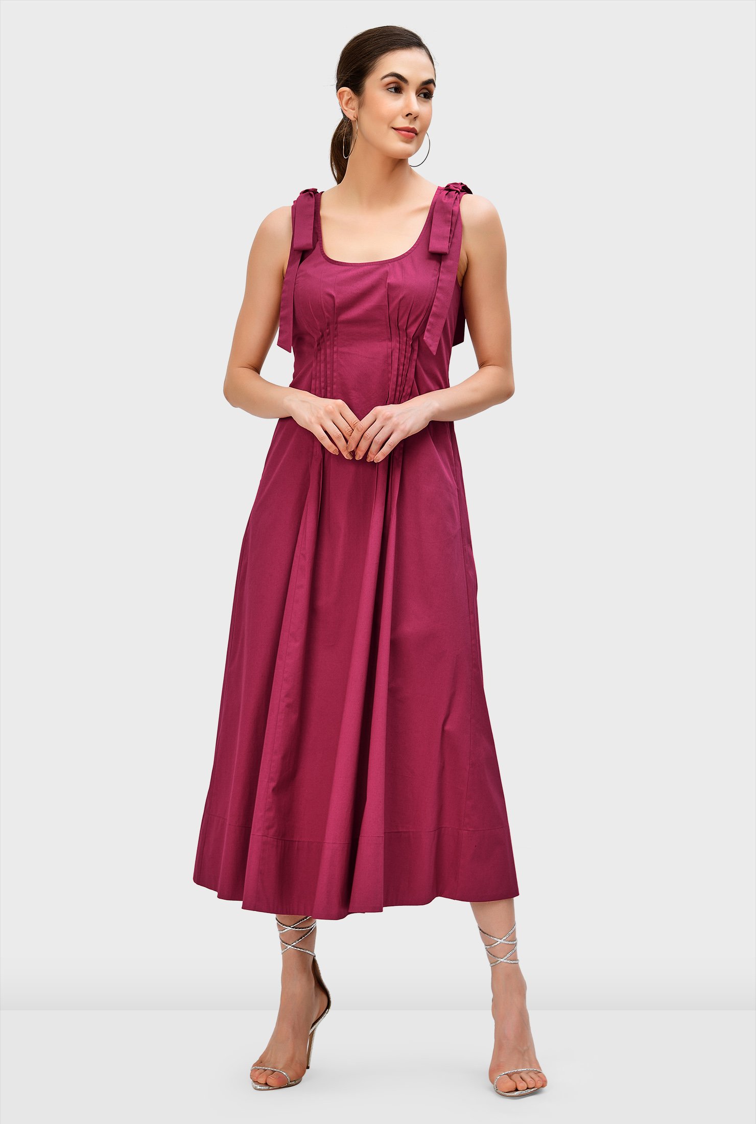 The sweet drape of bows beautifully top our crisp cotton poplin dress textured with pintuck pleats that cinch in the waist and release at the bodice as well as the full flare skirt.