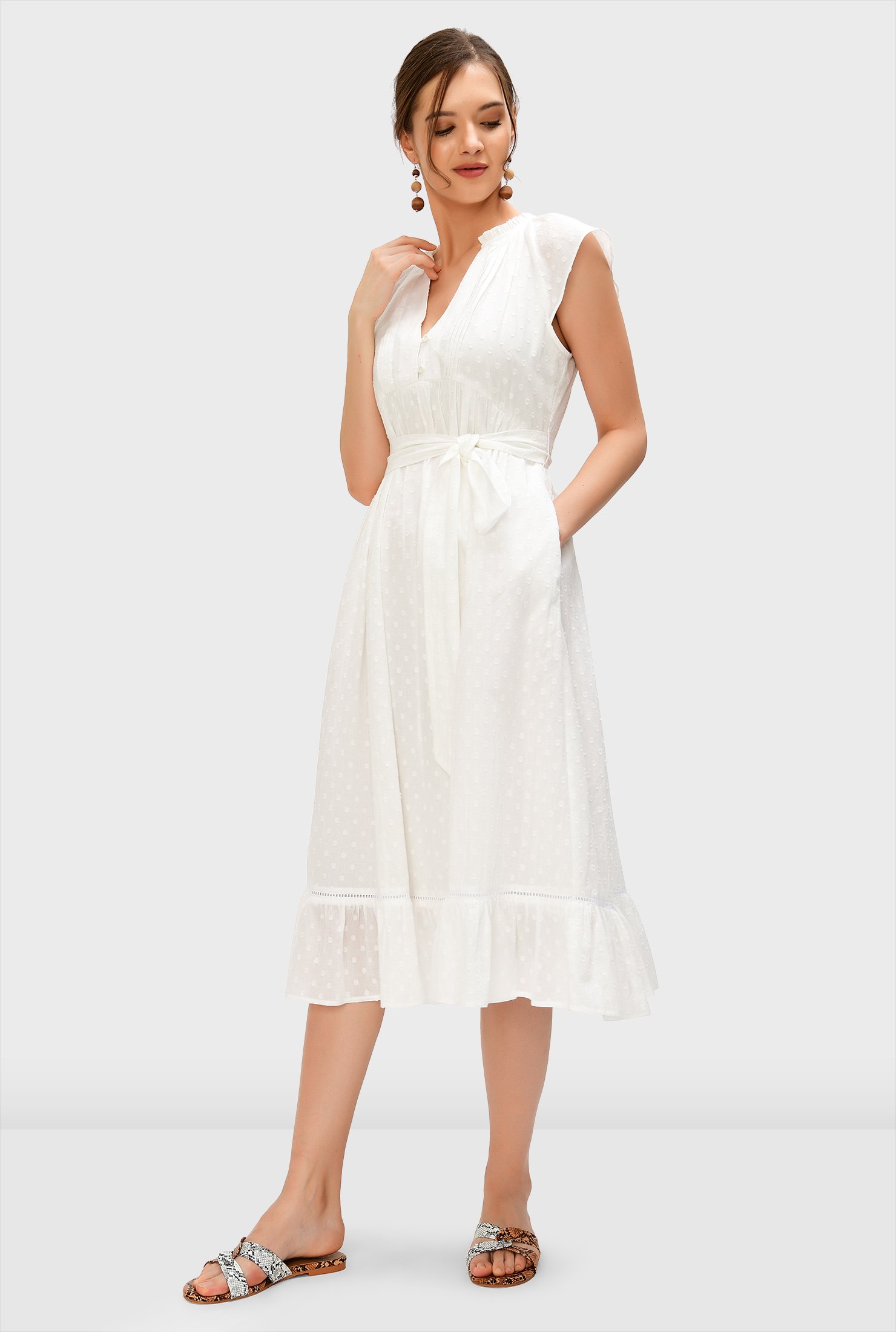 The perfect summer dress, our weightless white crafted from swiss dot cotton voile with a short rouleau-button front and relaxed empire waist floats down to a ruffle flounce hem.